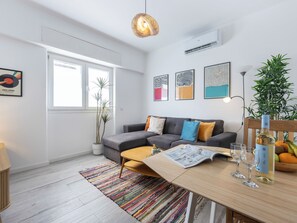 Un salon moderne avec un canapé, une table basse et une table à manger, ainsi que des verres et une bouteille.