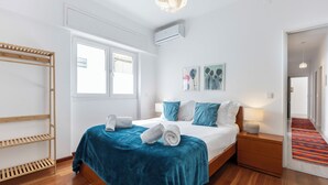 A modern bedroom with a bed, a wooden shelf, a window, and a hallway. - Casa Sardinha - in the heart of Portimão (Portimão)