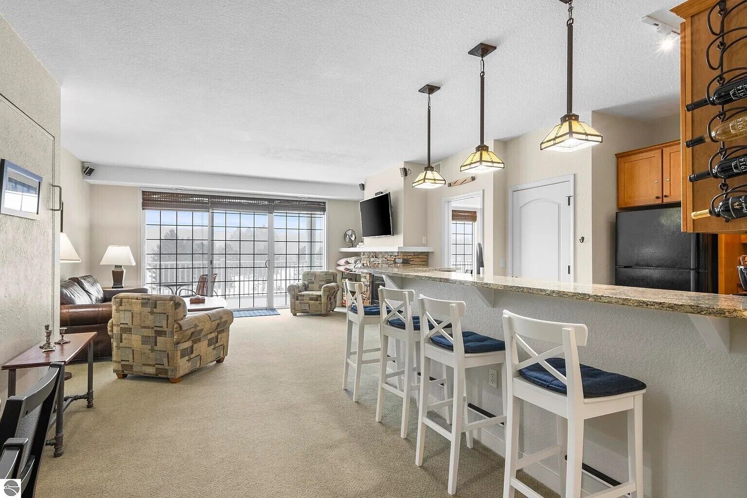 A modern kitchen with a bar area, a dining set, and a large window.