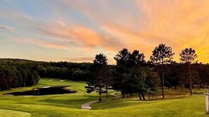 Un campo de golf con un estanque, árboles y cielo despejado.
