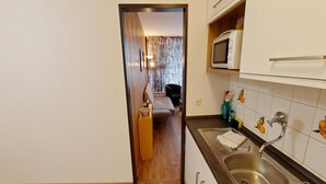 Kompakti keittiö, jossa on mikroaaltouuni, pesuallas ja puulattia.