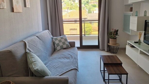 Ein modernes Wohnzimmer mit einer Couch, einem Couchtisch und einem Fernseher auf einem Schrank.