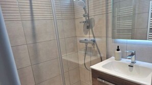 Ein modernes Badezimmer mit einer gläsernen Dusche, einem weißen Waschbecken und einer Holzausstattung.