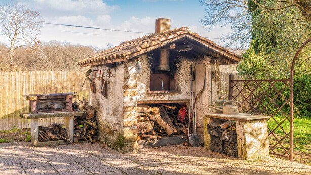 A rustic outdoor kitchen with a chimney, a wood-fired oven, and a stone table. - Country House - Isola dei Cavalli (Manziana)