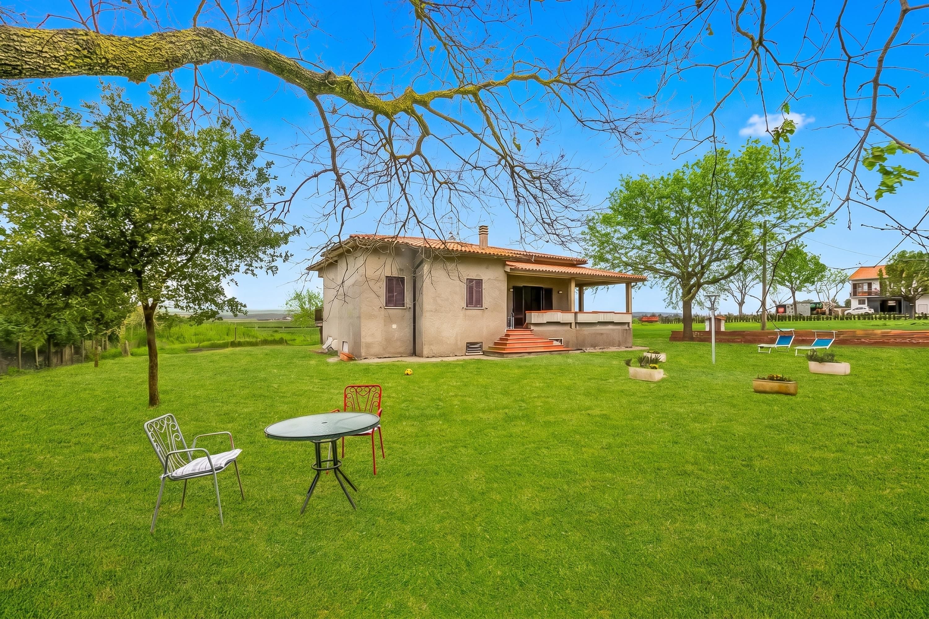 Una casa con un patio, un pequeño jardín y un césped.