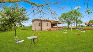 Una casa con un patio, un pequeño jardín y un césped.
