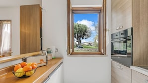 A compact kitchen with a window, a toaster, and a bowl of fruit on the counter. - House Tiziana Close by Mare Argentario (Manciano)