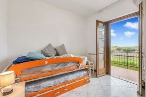 A bedroom with a bed, pillows, a lamp, and a view through an open door. - House Tiziana Close by Mare Argentario (Manciano)