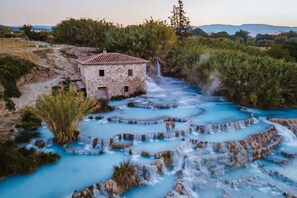A stone building with a tiled roof near a cascading waterfall and terraced pools of clear water. - House Tiziana Close by Mare Argentario (Manciano)
