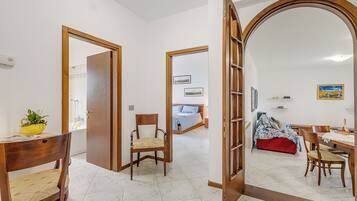 Una habitación con una mesa de comedor de madera, sillas, un sofá rojo y una cama con una manta azul.