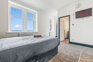 A bedroom with a bed, a window, a door, and a wall-mounted TV labeled 'NETFLIX'. - Eden View Flower Room (Lake District)