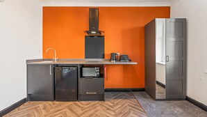 A compact kitchen with a dishwasher, a small refrigerator, a microwave, and a coffee maker on a countertop. - Eden View Jungle Room (Lake District)