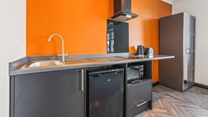 A compact kitchen with a sink, a built-in oven, and a compact refrigerator. - Eden View Jungle Room (Lake District)