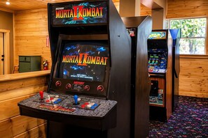 A retro arcade with a Mortal Kombat II game machine, wooden walls, and a carpeted floor.