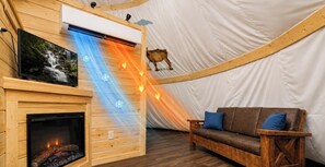 Ein gemütlicher Innenraum mit Kamin, Fernseher und einer Couch.