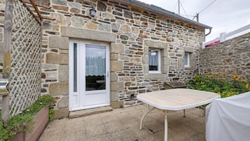 A stone building with a white door, a small window, and a table with a white tablecloth.