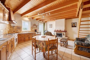 Eine geräumige Küche mit Holzschränken, einem Esstisch und einem Kamin.