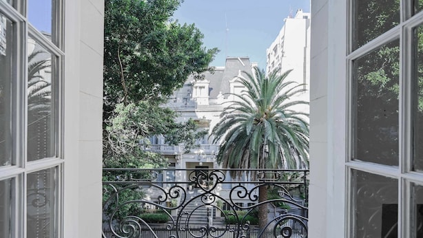 A balcony with wrought iron railings, a palm tree, and a building with classical architecture in the background. - LDV Aparts 2E by MOT Rentals (Buenos Aires)