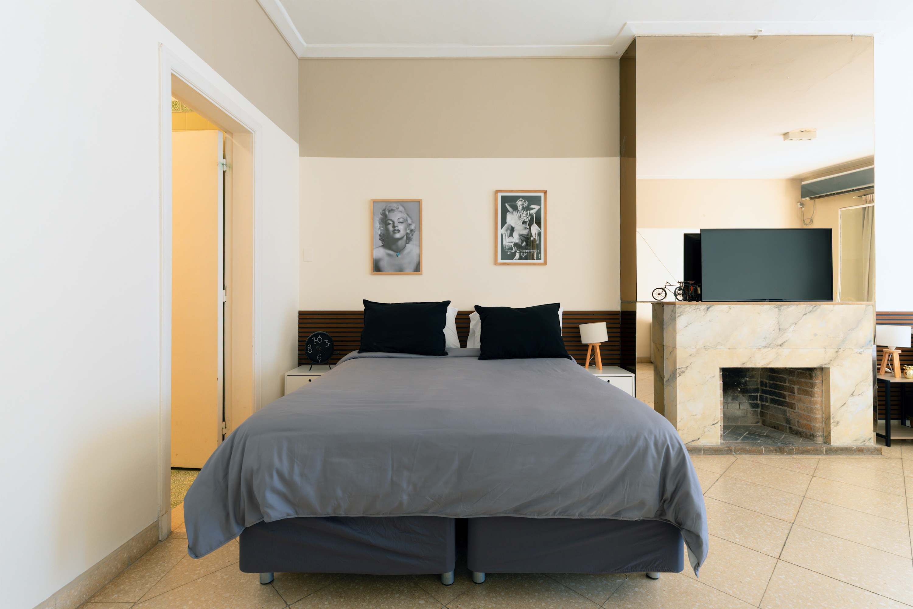 Una habitación de hotel con una cama grande, una chimenea, un televisor y dos cuadros en la pared.