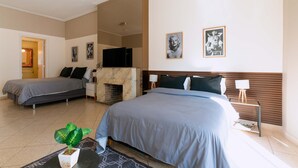 Ett hotellrum med två sängar, en öppen spis och konstverk på väggarna.