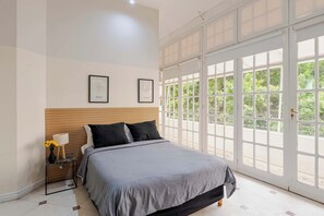 A bedroom with a bed, a nightstand, a lamp, and a large window with a view of greenery. - LDV Aparts 3D (2 Bedrooms) by MOT Rentals (Buenos Aires)