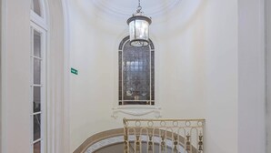 Un couloir avec un escalier, une lanterne suspendue et une porte avec une pancarte.