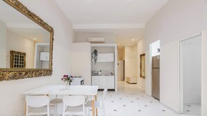 Une cuisine moderne avec des meubles blancs, un four à micro-ondes et un évier. On y trouve également un coin repas avec une table et des chaises blanches.