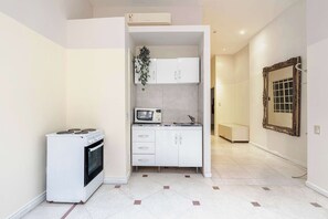 A compact kitchen with a stove, microwave, and white cabinets. - LDV Aparts 3D (2 Bedrooms) by MOT Rentals (Buenos Aires)