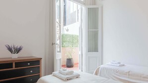Een slaapkamer met twee bedden, een houten dressoir en een kamerplant.