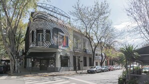 Een gebouw met een uniek architectuurontwerp, een etalage en geparkeerde auto's langs de straat.