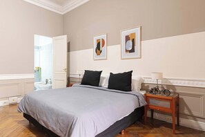 Ein Schlafzimmer mit einem Bett, einem Nachttisch, einer Lampe und zwei gerahmten Bildern an der Wand.