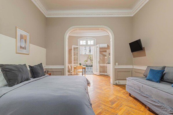 A bedroom with a bed, a sofa, a TV, and an open door leading to a balcony. - LDV Aparts 2B by MOT Rentals (Buenos Aires)