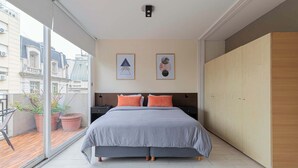 Ein Schlafzimmer mit einem großen Bett, einem Kleiderschrank und einem Balkon mit Blumentöpfen.
