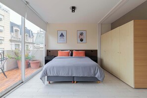 A bedroom with a large bed, a wardrobe, and a balcony with potted plants. - LDV Aparts 5A by MOT Rentals (Buenos Aires)