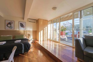 A modern hotel room with a bed, a sofa, a small table, and a large window offering a city view. - LDV Aparts 6B by MOT Rentals (Buenos Aires)