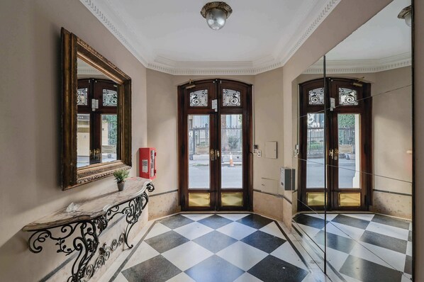 A hallway with a checkered floor, a marble bench, and a large mirror on the wall. - LDV Aparts 3B by MOT Rentals (Buenos Aires)