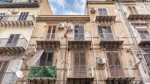 Un edificio de varios pisos con balcones, unidades de aire acondicionado y una antena parabólica.