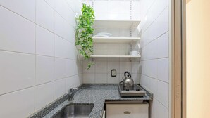Een compacte keuken met een granieten aanrechtblad, een roestvrijstalen spoelbak en een kleine inbouwoven.