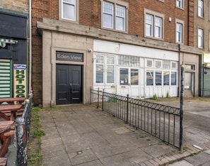 Un edificio con un letrero que dice 'Eden View' y una tienda cerrada con una valla metálica al frente.