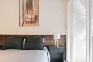 A bedroom with a bed, pillows, a nightstand, a lamp, a mirror, and a door. - LDV Aparts 5B by MOT Rentals (Buenos Aires)