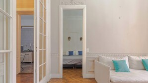 A room with a wooden floor, a white sofa with teal cushions, and a bed with blue and white pillows. - LDV Aparts 2A (2 Bedrooms) by MOT Rentals (Buenos Aires)