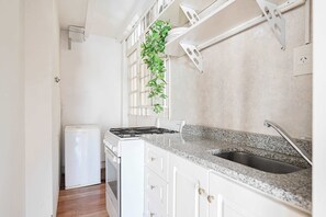 A kitchen with white cabinets, a granite countertop, a stainless steel sink, and a small refrigerator. - LDV Aparts 6A (Private Pool) by MOT Rentals (Buenos Aires)
