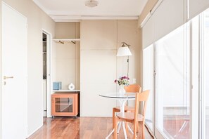 A room with a glass table, wooden chairs, a lamp, a vase with flowers, and a sliding door. - LDV Aparts 6A (Private Pool) by MOT Rentals (Buenos Aires)