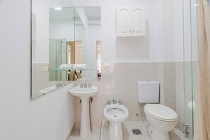 A bathroom with a sink, bidet, toilet, and a mirror. - LDV Aparts 4E by MOT Rentals (Buenos Aires)
