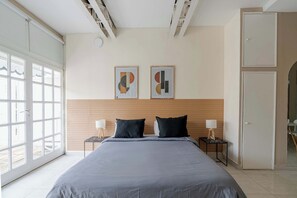 A bedroom with a large bed, two bedside tables with lamps, a wooden headboard, and two abstract paintings on the wall. - LDV Aparts 4E by MOT Rentals (Buenos Aires)