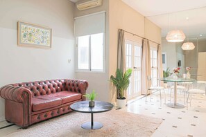 A living room with a leather sofa, a round coffee table, and a glass dining table with chairs. - LDV Aparts 2F by MOT Rentals (Buenos Aires)