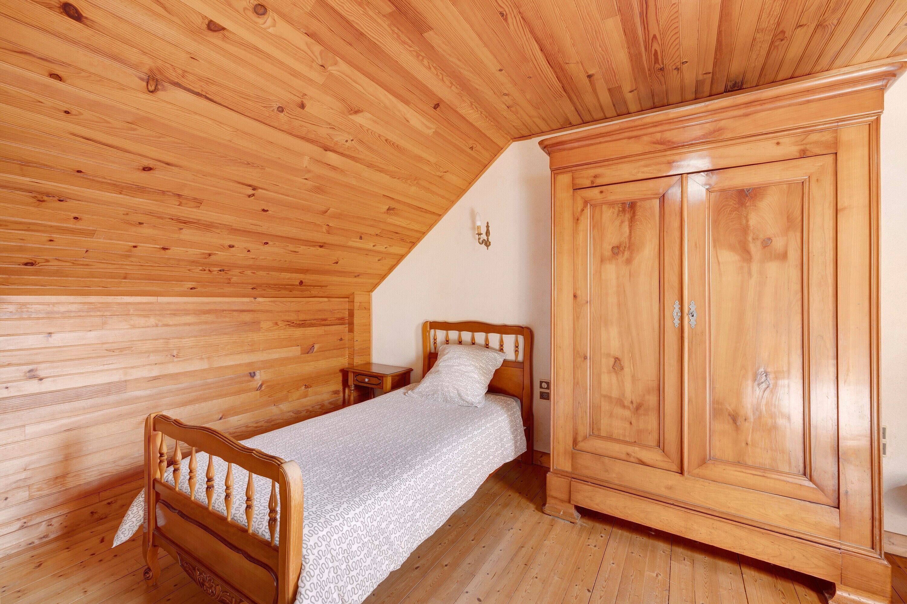 A wooden-paneled room with a bed, nightstand, and wardrobe.