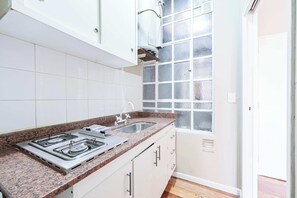 Eine Küche mit weißen Schränken, einer Granitarbeitsplatte, einem Gasherd und einem Fenster mit Milchglas.