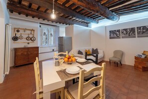Un coin repas avec une table en bois, des chaises, un buffet blanc et une cuisine en arrière-plan.