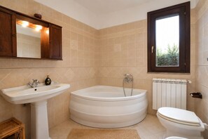 Een badkamer met een wastafel, bad, toilet en een raam met uitzicht.
